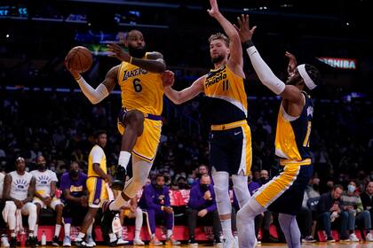 LeBron James (6), de los Lakers de los Ángeles, realiza un pase ante la presión de los jugadores de los Pacers de Indiana Domantas Sabonis (11) y Oshae Brissett (12) en la primera mitad del juego de la NBA que enfrentó a ambos equipos en Los Ángeles, el 19 de enero de 2022. (AP Foto/Ashley Landis)