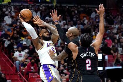 LeBron James (6), de los Lakers de Los Ángeles, intenta pasar el balón con la marca de P.J. Tucker, centro, y Gabe Vincent (2), del Heat de Miami, durante la primera mitad del juego de la NBA, el domingo 23 de enero de 2022, en Miami. (AP Foto/Lynne Sladky)