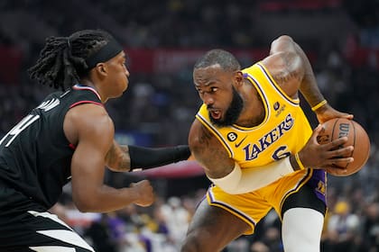 LeBron James (derecha), de los Lakers de Los Ángeles, trata de superar a Terance Mann, de los Clippers, en la primera mitad del juego de la NBA que enfrentó a ambos equipos, el 9 de noviembre de 2022, en Los Ángeles. (AP Foto/Mark J. Terrill)