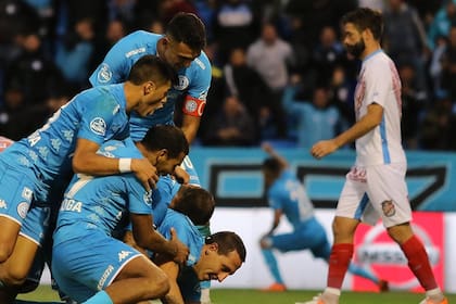 Lema, casi en el piso, objeto de los abrazos: el defensor marcó dos goles para Belgrano, que le ganó 3-0 a Arsenal