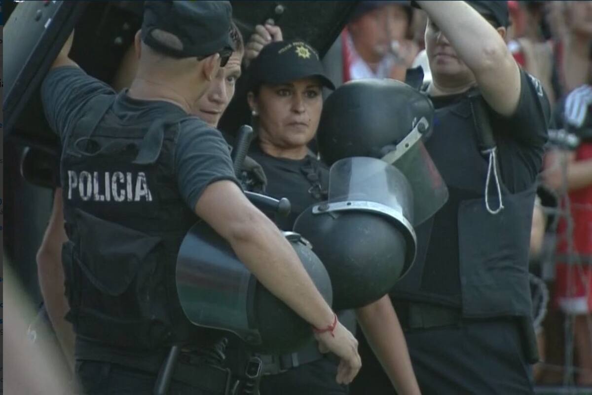 Leo Gil, custodiado por los policías para que pueda ejecutar un córner en el clásico de Rosario