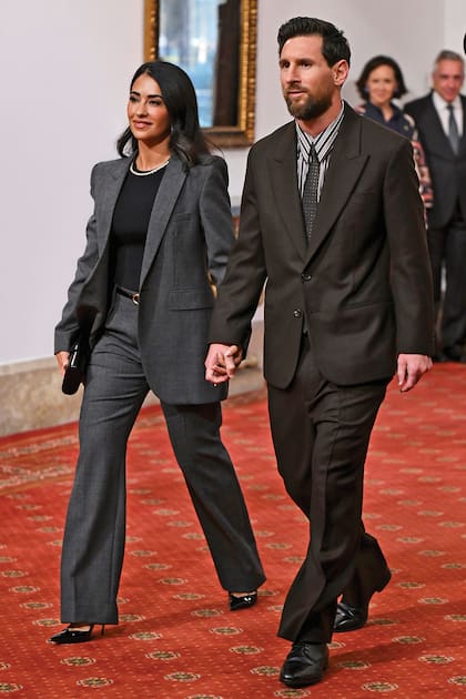 Leo y Antonela –que optó por un estilismo minimalista: traje gris de pantalón y chaqueta, que acompañó con top negro, stilettos al tono y un delicado collar de diamantes Tiffany & Co– entran al Hotel de la Reconquista