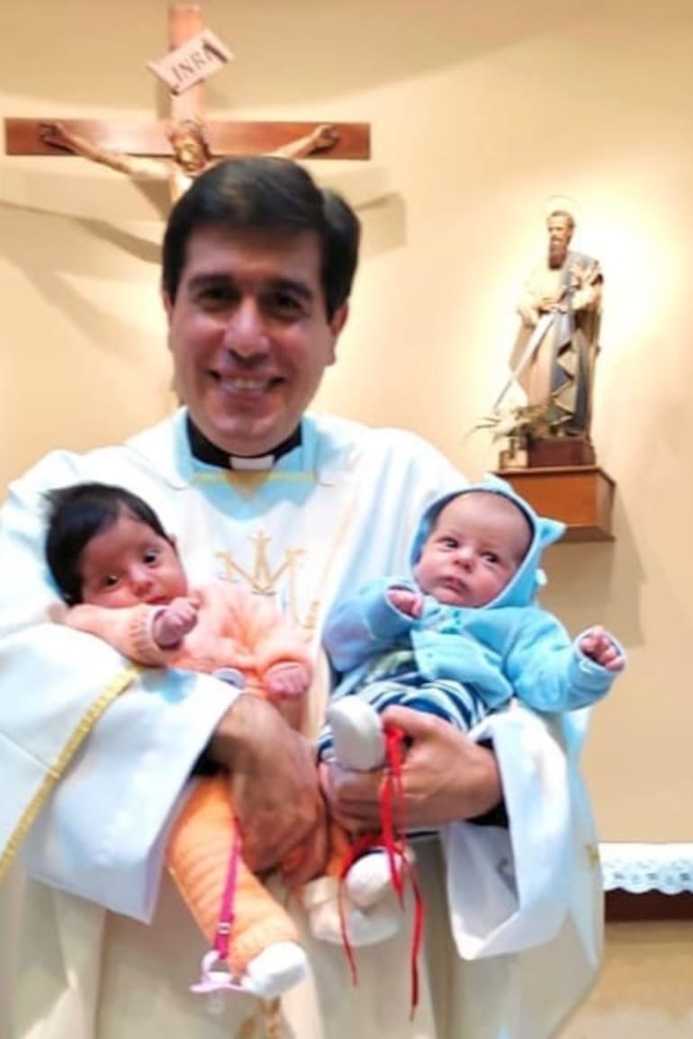 Leonardo Di Carlo, con dos bebés en brazo, frente al altar de su parroquia