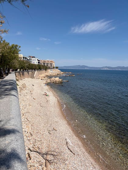 L’Escala conserva sus calles estrechas con construcciones blancas y calas urbanas bañando playas de canto rodado, tan clásicas de la costa catalana. Acá, la playa de El Codolar y, de fondo, el perfil montañoso en torno al Golfo de Roses.