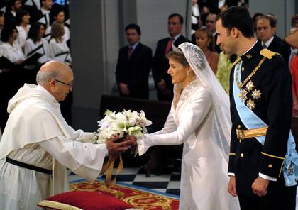 Letizia entrega el ramo a un sacerdote. La futura reina lucía unos pendientes de platino con 10 diamantes regalo de sus suegros y la tiara que lució la reina Sofía en su boda en Atenas, conocida como ‘La Prusiana’, de estilo neoclásico, que ya llevó la madre de doña Sofía, la reina Federica, en su boda con el rey Pablo de Grecia. El ramo de la novia, en forma de cascada, estaba compuesto por lirios (uno de los símbolos de la realeza), rosas y azahar (homenaje a la condesa de Barcelona), flor de manzano (por el Principado de Asturias) y espigas (símbolo de fertilidad, esperanza y alegría)