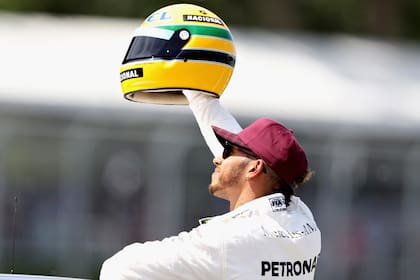 Lewis Hamilton y un casco conmemorativo de Ayrton Senna, luego de batir el récord de 65 pole positions en el circuito de Silverstone; el paulista logró su primer triunfo en la Fórmula 1 en Portugal, en 1985, país en donde el británico impuso una nueva marca de triunfos