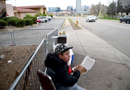 Lincoln Montero come fuera de un motel para migrantes después de ayudar a su tía Yesenia a vender comida casera al estilo venezolano a otros migrantes venezolanos refugiados en Denver, Colorado. (AP Foto/Thomas Peipert)