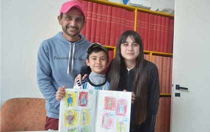 Lionel, junto a su padre Darío y su hermana Brisa, mostrando el álbum improvisado de figuritas
Foto: Fernanda Miranda / Diario de La República