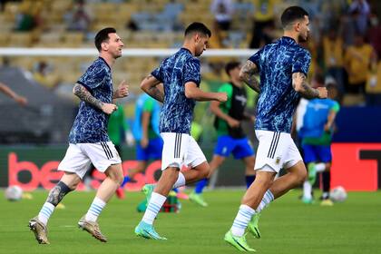 Lionel Messi, Cristian Romero y Leandro Paredes realizan el calentamiento previo a la final de la Copa América sobre el césped del estadio Maracaná.