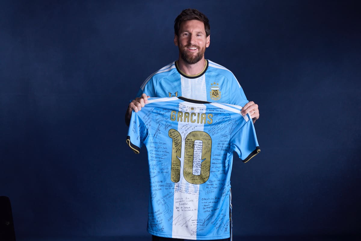 Lionel Messi sostiene la camiseta especial de su despedida, firmada por sus compañeros de la selección argentina