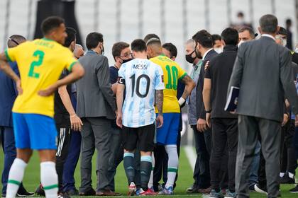 Lionel Messi y Neymar charlan con un agente sanitario luego que el partido entre Argentina y Brasil por las eliminatorias del Mundial fue interrumpido, el domingo 5 de septiembre de 2021. (AP Foto/Andre Penner)
