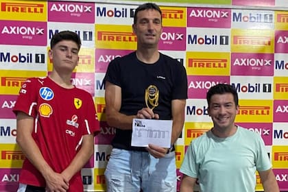 Lionel Scaloni exhibe la planilla de tiempos de la carrera y el trofeo por haber ganado en un kartódromo de Rosario entre familiares y amigos.