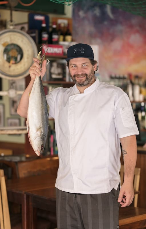 Lisandro Ciarlotti, cocinero y creador de Lo de Tata, sostiene un pez limón de la pesca del día.