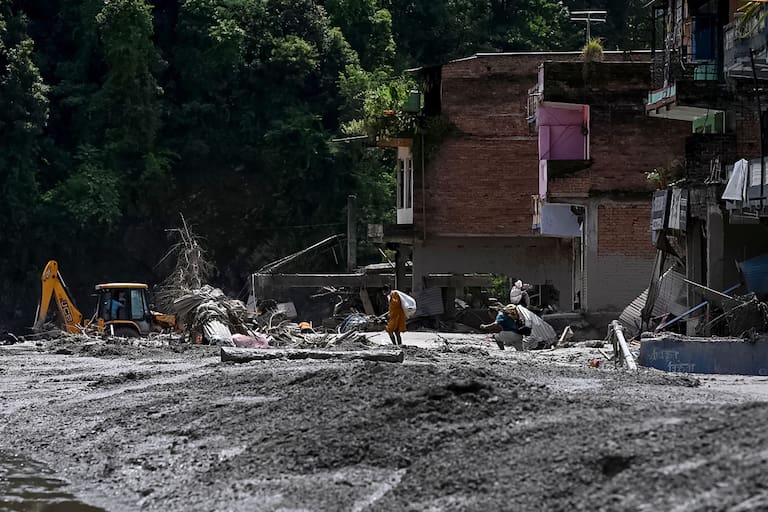Local residents salvage their belongings from houses lying deluged in sludge after flash floods in the Devighat area in Nepal's Nuwakot district on August 27, 2026. Rescue teams rushed on August 27 to find more than 1,300 people missing on the Nepal-Tibet border in flash floods and landslides that killed at least 165 and swept away entire villages. (Photo by Prakash MATHEMA / AFP)