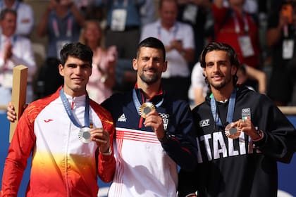 Lorenzo Musetti, medallista de bronce, junto con Alcaraz (plata) y Djokovic, en la ceremonia de premiación olímpica, en el Philippe-Chatrier