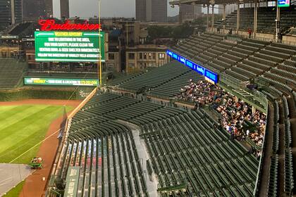 Los aficionados se cubren de la lluvia que obligó a suspender el encuentro entre los Cerveceros de Milwaukee y los Cachorros de Chicago en el Wrigley Field, en Chicago, el lunes 9 de agosto del 2021. El encuentro se disputará el martes. (AP Photo/Charles Rex Arbogast)