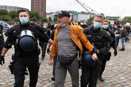 Los agentes de policía se llevan a un manifestante durante una manifestación contra las restricciones establecidas para limitar la propagación de la pandemia de coronavirus el 23 de mayo de 2020 en Frankfurt