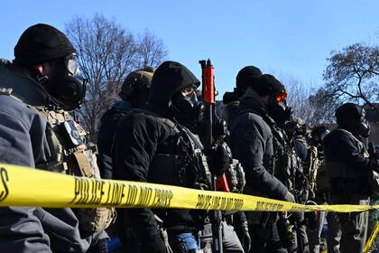 Los agentes del ICE se plantan frente a los manifestantes en la escena del tiroteo donde fue baleado un civil