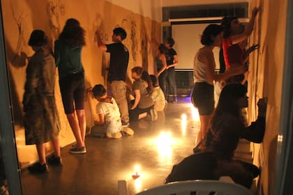Los alumnos del artista Max Gómez Canle dibujan en paredes forradas de papel a la luz de las velas