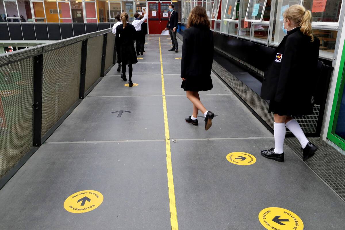 Los alumnos siguen las señales de distanciamiento social mientras caminan por un pasillo en la Kingsdale Foundation School en Londres.