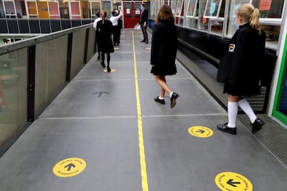 Los alumnos siguen las señales de distanciamiento social mientras caminan por un pasillo en la Kingsdale Foundation School en Londres.