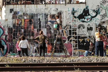 Los artistas del taller Paredón en pleno montaje de un mural callejero