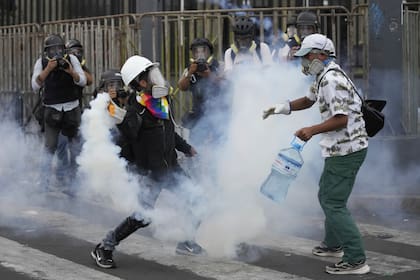 Los así llamados "desactivadores" trabajan para neutralizar un bote de gas lacrimógeno durante una protesta antigubernamental el sábado 28 de enero de 2023, en Lima, Perú.