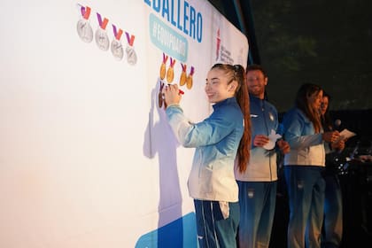 Los atletas pegaron sus medallas simbólicas en un panel y las autografiaron