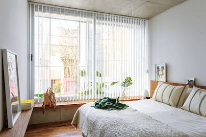 Los bancos de pino tea recuperada de la obra moderan la relación con el exterior. Pashmina y almohadones en tussor estampado (Petite Margot).