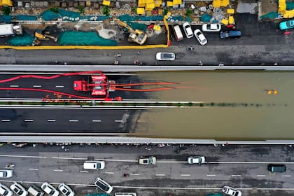 Los bomberos bombean agua de lluvia desde un paso subterráneo de una carretera en Zhengzhou, en la provincia de Henan