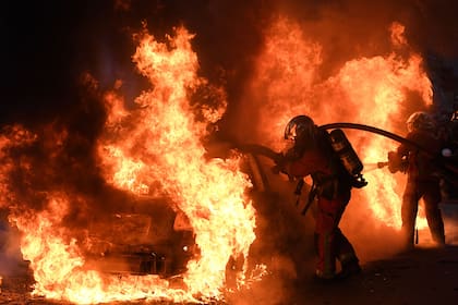 Los bomberos intentan apagar el fuego desde un automóvil durante una protesta contra el proyecto de ley de seguridad global