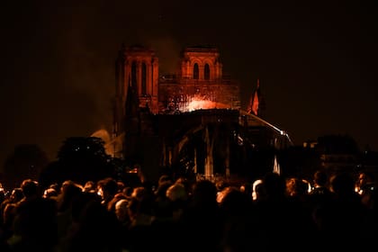 Los bomberos intentan apagarl el fuego, ante la mirada atónita de parisinos y turistas