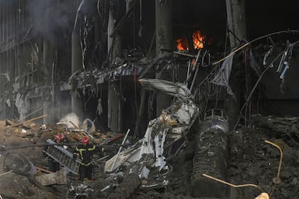 Los bomberos llevan un cargador mientras se abren paso entre los escombros tras los bombardeos rusos que destruyeron el centro comercial Retroville en Kiev el 21 de marzo de 2022