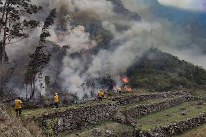 Los bomberos trabajan para apagar un incendio en los arbustos que rodean las ruinas de Llamakancha, un sector en el sitio arqueológico de Machu Picchu, la joya inca de la industria turística de Perú, en las tierras altas cerca de la ciudad del Cusco. (Photo by Jesus TAPIA / Machu Picchu Municipality / AFP)