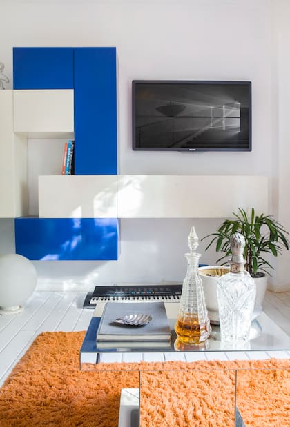 Los cajones que enmarcan la tele, laqueados en dos colores, son diseño del dueño de casa, igual que el sillón.