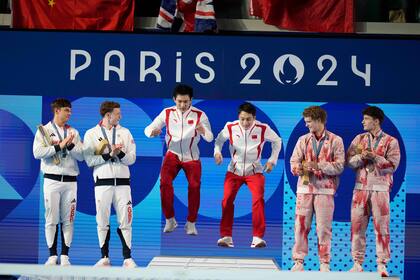Los chinos Lian Junjie y Yang Hao, centro, festejan su medalla de oro flanqueados por los medallistas de plata, los británicos Thomas Daley y Noah Williams, izquierda, y los de bronce, Rylan Wiens y Nathan Zsombor-Murray, de Canadá, en el podio de plataforma sincronizada para hombres de los Juegos Olímpicos de París 2024 el lunes 29 de julio de 2024, en Saint-Denis, Francia. (AP Foto/Lee Jin-man)