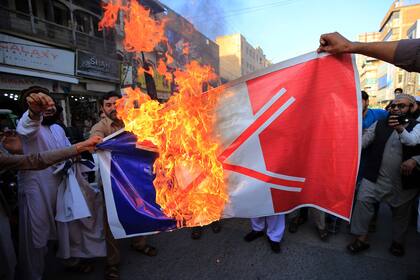 Los comerciantes queman una bandera nacional francesa durante una protesta tras los comentarios del presidente francés Emmanuel Macron sobre las caricaturas del profeta Mahoma, en Peshawar el 26 de octubre de 2020