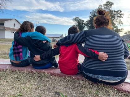 Los cuatro hermanos, unidos en un abrazo en el jardín del hogar para chicos donde viven, en Almirante Brown