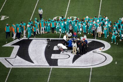 Los Dolphins de Miami observan la atención a su compañero, el quarterback Tua Tagovailoa (1), quien sufrió una conmoción cerebral durante el partido del jueves 29 de septiembre de 2022, ante los Bengals de Cincinnati (AP Foto/Emilee Chinn)