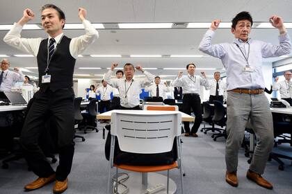 Los empleados de una empresa de tecnología mientras hacen ejercicios en sus oficina, después de la hora del almuerzo en Tokio.