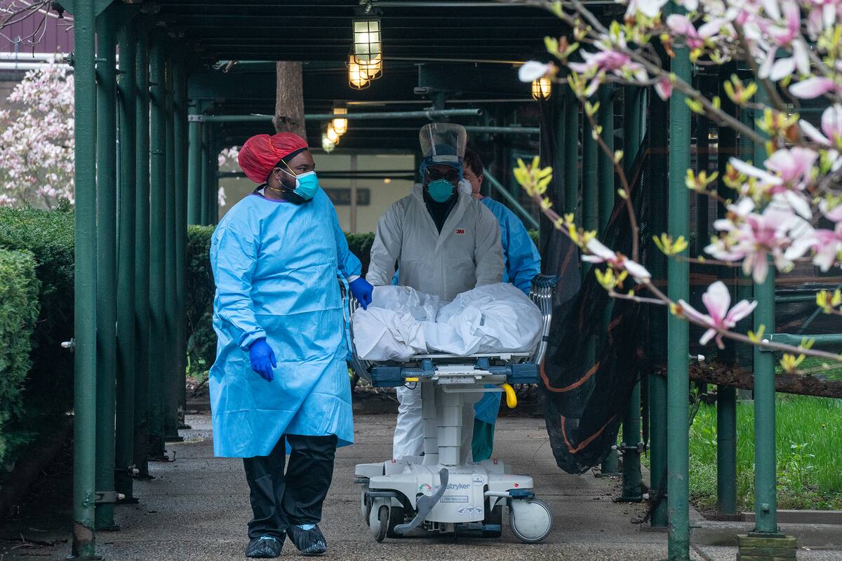 Los empleados del Kingsbrook Jewish Medical Center transportan a un paciente fallecido a un camión refrigerado el 8 de abril de 2020 en el distrito de Brooklyn de la ciudad de Nueva York