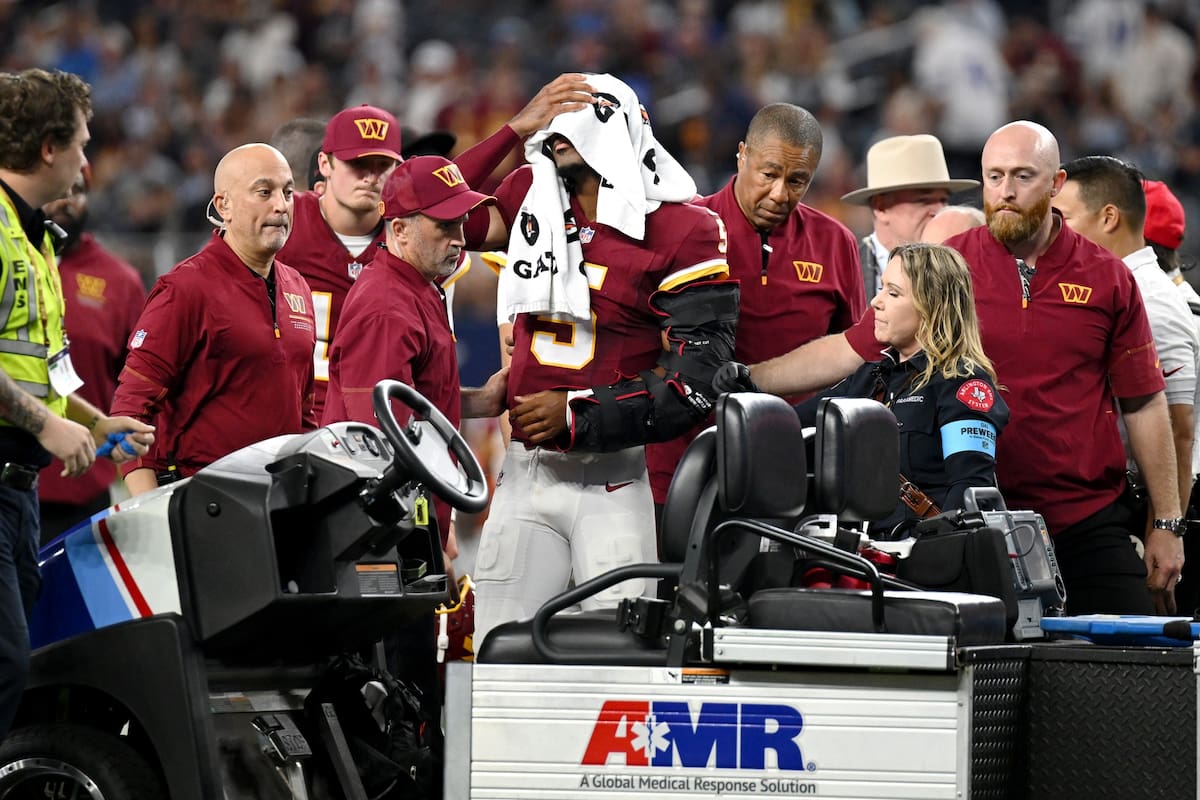 Los entrenadores atienden al quarterback de los Commanders de Washington, Jayden Daniels (5), tras u