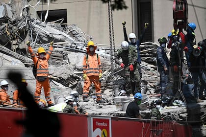 Los equipos de rescate piden silencio durante la búsqueda de sobrevivientes entre los escombros de un edificio derrumbado en Cali, Colombia, el 13 de agosto de 2026 (Joaquin Sarmiento / AFP)