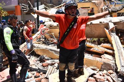Los equipos de rescate se paran junto a un automóvil aplastado por los escombros a causa de un terremoto, en Cuenca, Ecuador, el sábado 18 de marzo de 2023. El Servicio Geológico de EEUU reportó el sismo de magnitud 6,7 a unas 50 millas al sur de Guayaquil. (Foto AP/Xavier Caivinagua)