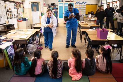 Los estudiantes de enfermería Soledad Lupian, a la izquierda, y Edwin Gituma mostraron a los alumnos de primer grado de la Escuela Primaria Ethel Phillips en Sacramento cómo lavarse las manos adecuadamente para reducir la propagación del coronavirus en marzo, antes de que cerraran las escuelas.