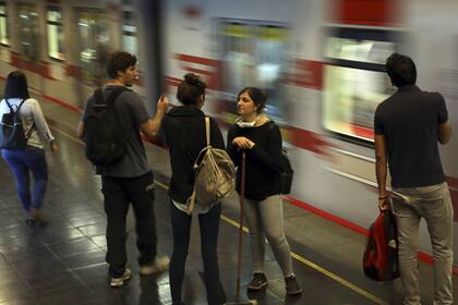 Los estudiantes esperan tomar el metro después de limpiar las calles dañadas por las protestas contra el gobierno de Piñera