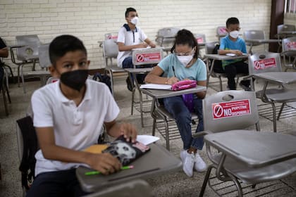 Los estudiantes se sientan con distancia durante la clase presencial en la Escuela Secundaria Técnica Industrial Número 26 de Veracruz, México, el lunes 30 de agosto de 2021, al iniciarse un nuevo año académico durante la pandemia de COVID-19. (AP Foto/Felix Marquez)