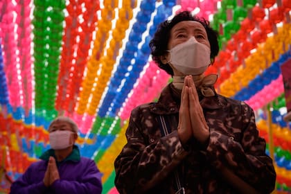 Los fieles, con barbijos, asisten a una ceremonia de oración titulada "Superar y sanar el coronavirus", mientras conmemoran el cumpleaños de Buddha en el templo budista Jogye en Seúl el 30 de abril de 2020