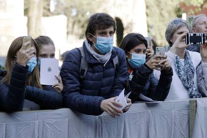 Los fieles usan barbijos mientras esperan la llegada del Papa Francisco fuera de la Basílica de Santa Sabina