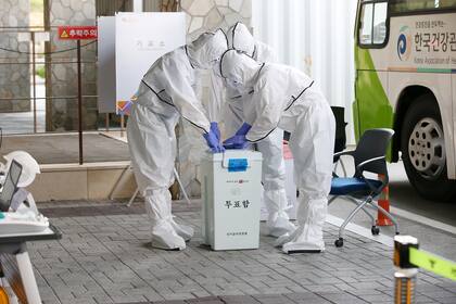 Los funcionarios electorales que usan ropa protectora establecieron un centro de votación en una instalación de cuarentena en Gyeongju el 10 de abril de 2020 antes de las elecciones parlamentarias de Corea del Sur